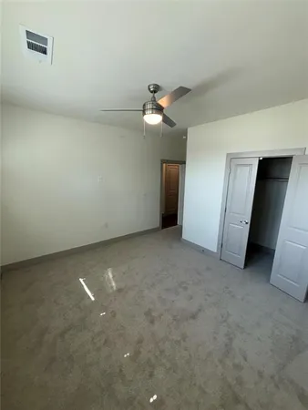 an empty room with closet and a ceiling fan
