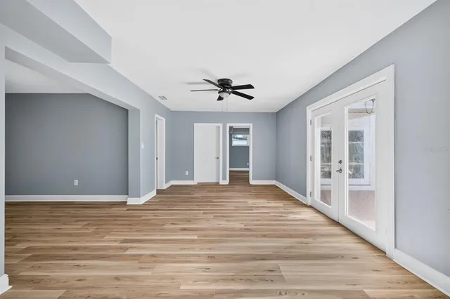 a view of empty room with wooden floor and ceiling fan