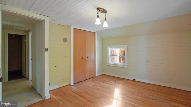 an empty room with wooden floor chandelier and window