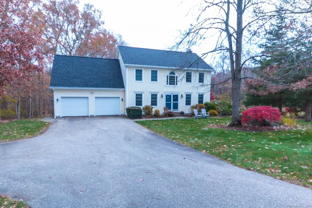 a front view of a house with a garden and tree