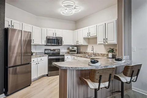 a kitchen with stainless steel appliances granite countertop a stove a refrigerator a sink a stove and a refrigerator