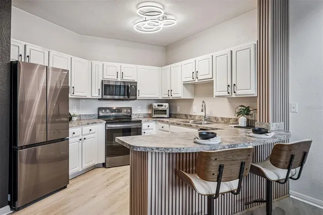 a kitchen with stainless steel appliances granite countertop a stove a refrigerator a sink a stove and a refrigerator