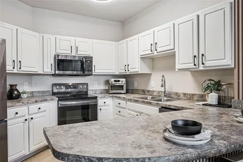 a kitchen with stainless steel appliances granite countertop a stove a sink dishwasher and a refrigerator with wooden cabinets