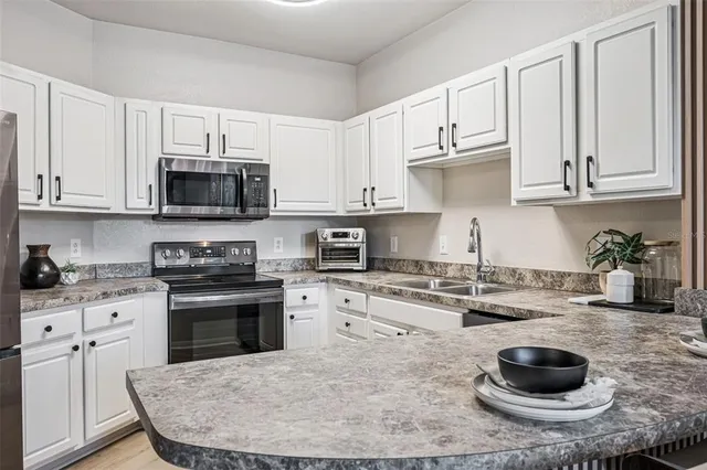 a kitchen with stainless steel appliances granite countertop a stove a sink dishwasher and a refrigerator with wooden cabinets