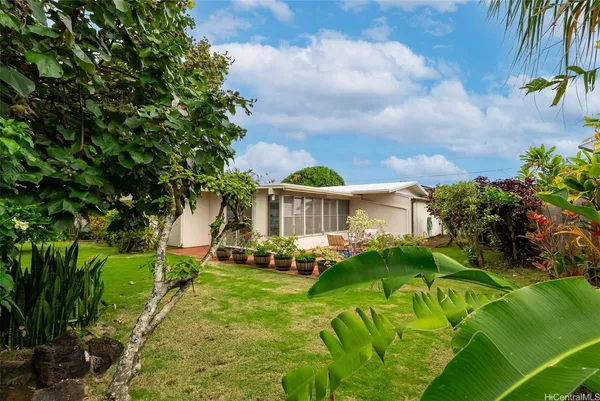 a view of a house with a big yard plants and large trees