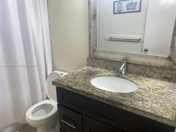a bathroom with a granite countertop sink toilet and shower