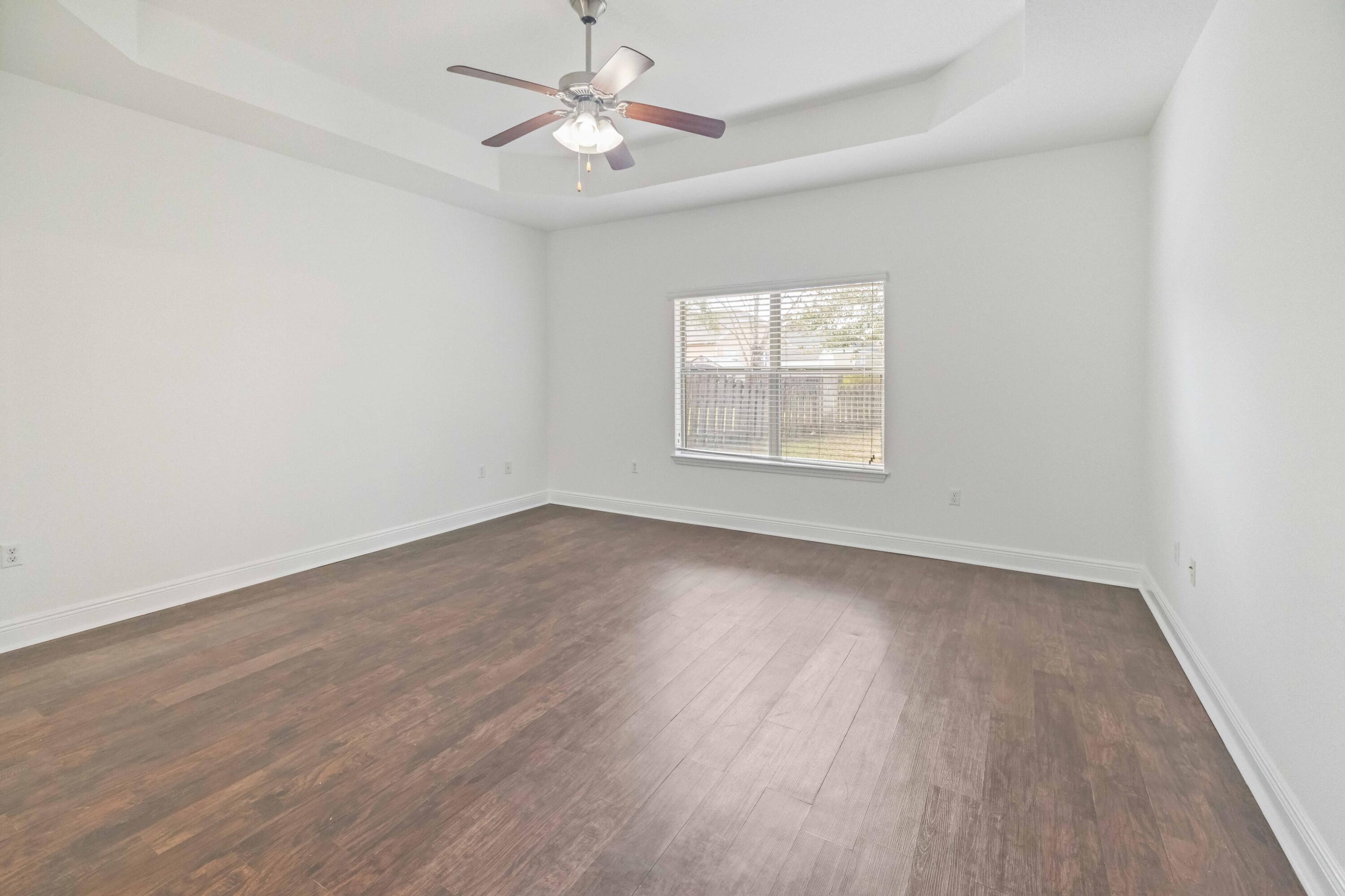 337 Mango Lane Freeport, FL 32439 - Photo 9 of 35 an empty room with wooden floor fan and windows
