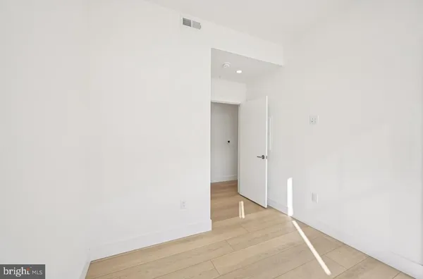 a view of an empty room with wooden floor and a bathroom