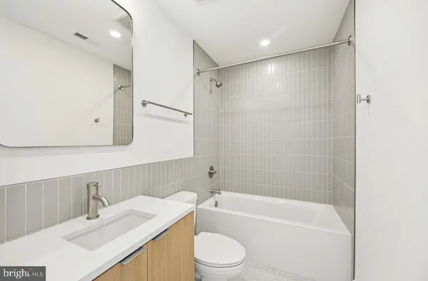 a bathroom with a bathtub shower sink vanity mirror and toilet