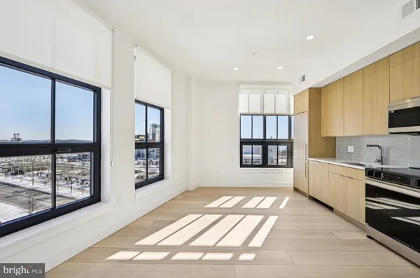 a large white kitchen with granite countertop a large window and stainless steel appliances