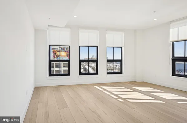 a view of an empty room with window and wooden floor