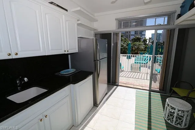 a kitchen with granite countertop a refrigerator a stove and white cabinets