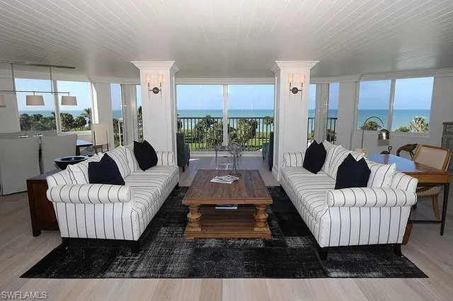 a living room with furniture floor to ceiling window and a table