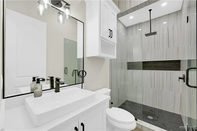a bathroom with a sink a toilet a mirror and shower