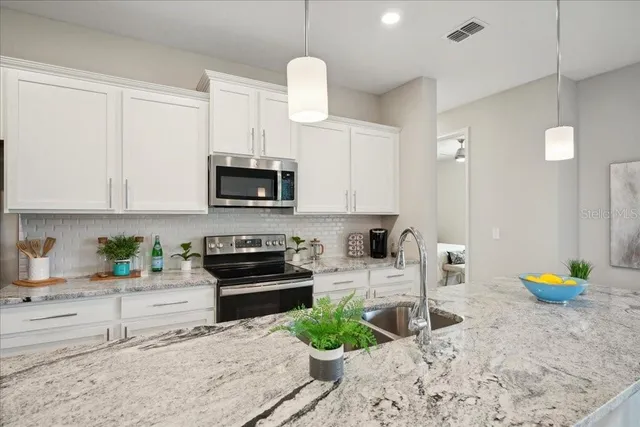 a kitchen with stainless steel appliances granite countertop a sink a stove cabinets and a counter top space