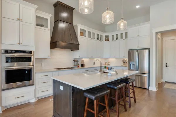 a kitchen with cabinets a sink dishwasher a stove and a dining table with wooden floor