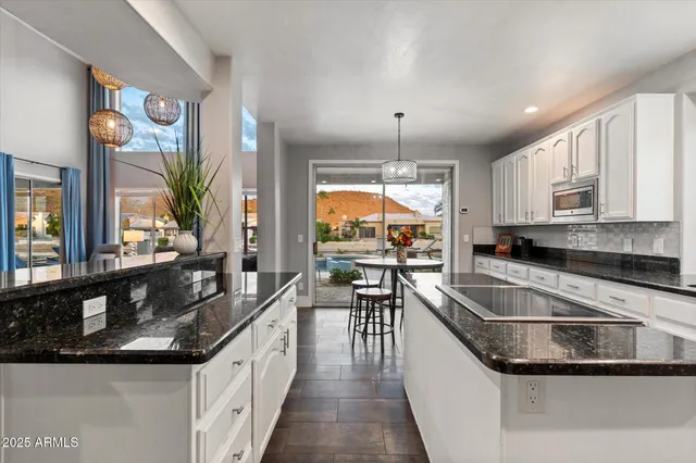 a kitchen with granite countertop a table chairs sink and refrigerator