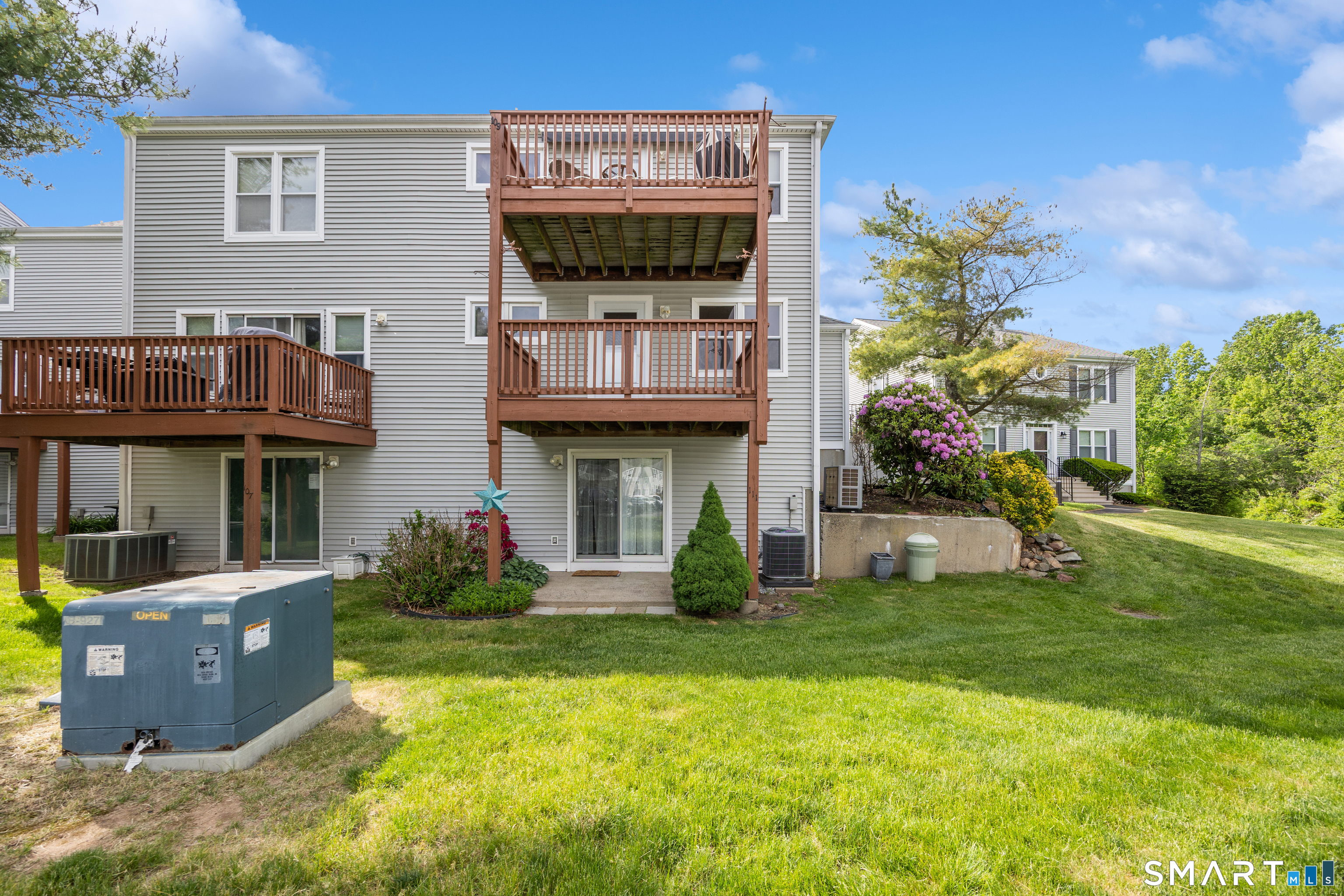 111 Strathmore Lane, Unit 111 Wallingford, CT 06492 - Photo 28 of 32 Rear of structure has well maintained green space and features the deck off of living room and the patio off lower level family room