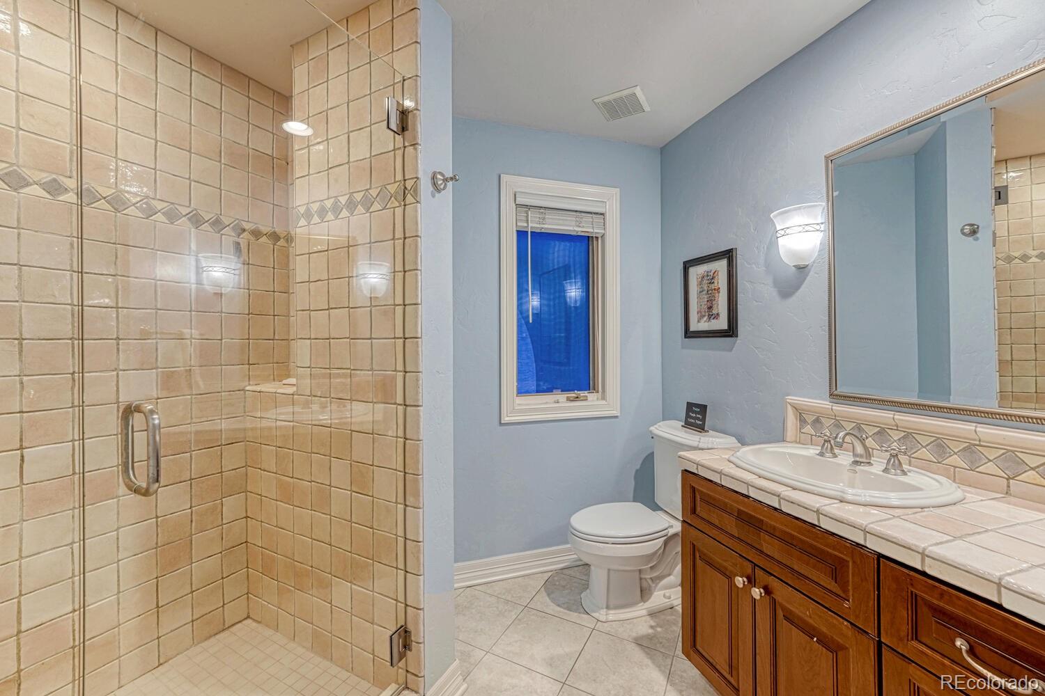 26344 Independence Trail Evergreen, CO 80439 - Photo 23 of 50 a bathroom with a granite countertop toilet a sink a shower and a mirror