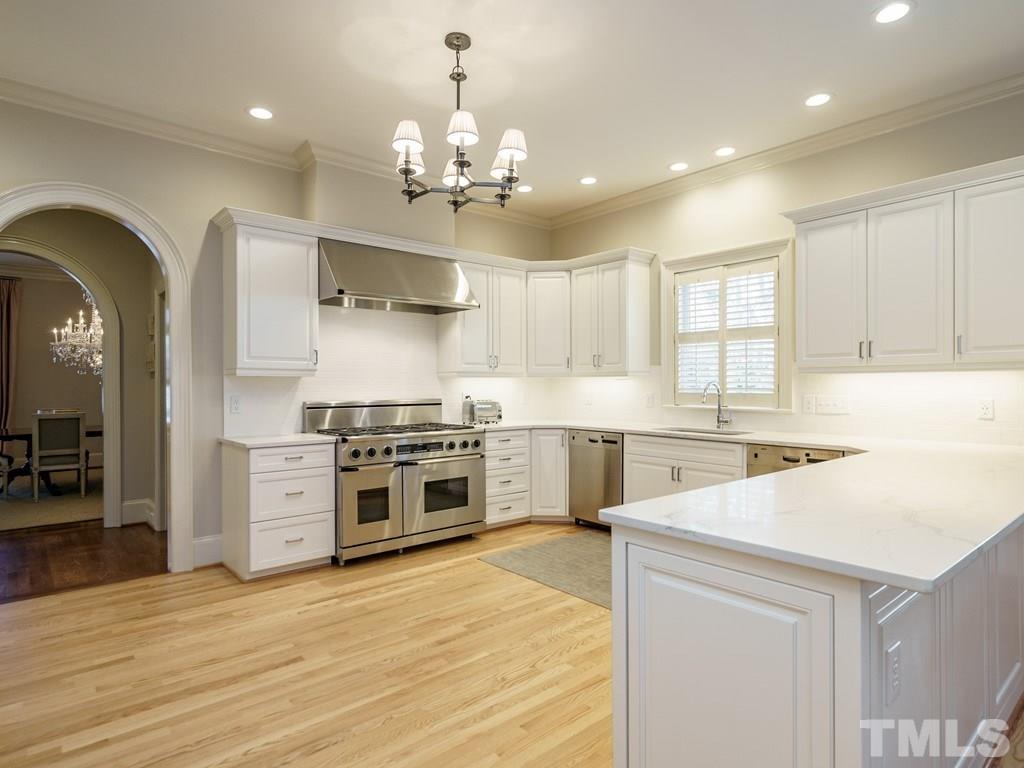 2304 White Oak Road Raleigh, NC 27608 - Photo 9 of 30 a large kitchen with stainless steel appliances a stove a sink dishwasher and a refrigerator with wooden floor