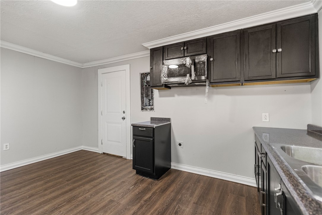 109 Farmer Street Anderson, SC 29621 - Photo 12 of 31 A compact kitchen featuring wood plank flooring and dark cabinetry, ready for personalized touches.