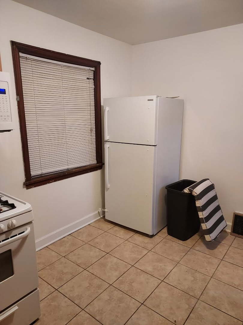 104 East 150th Street Harvey, IL 60426 - Photo 4 of 25 a kitchen with a refrigerator and white cabinets
