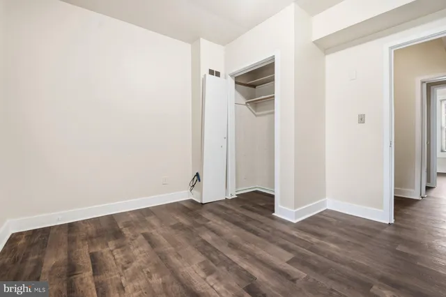 an empty room with wooden floor and closet area