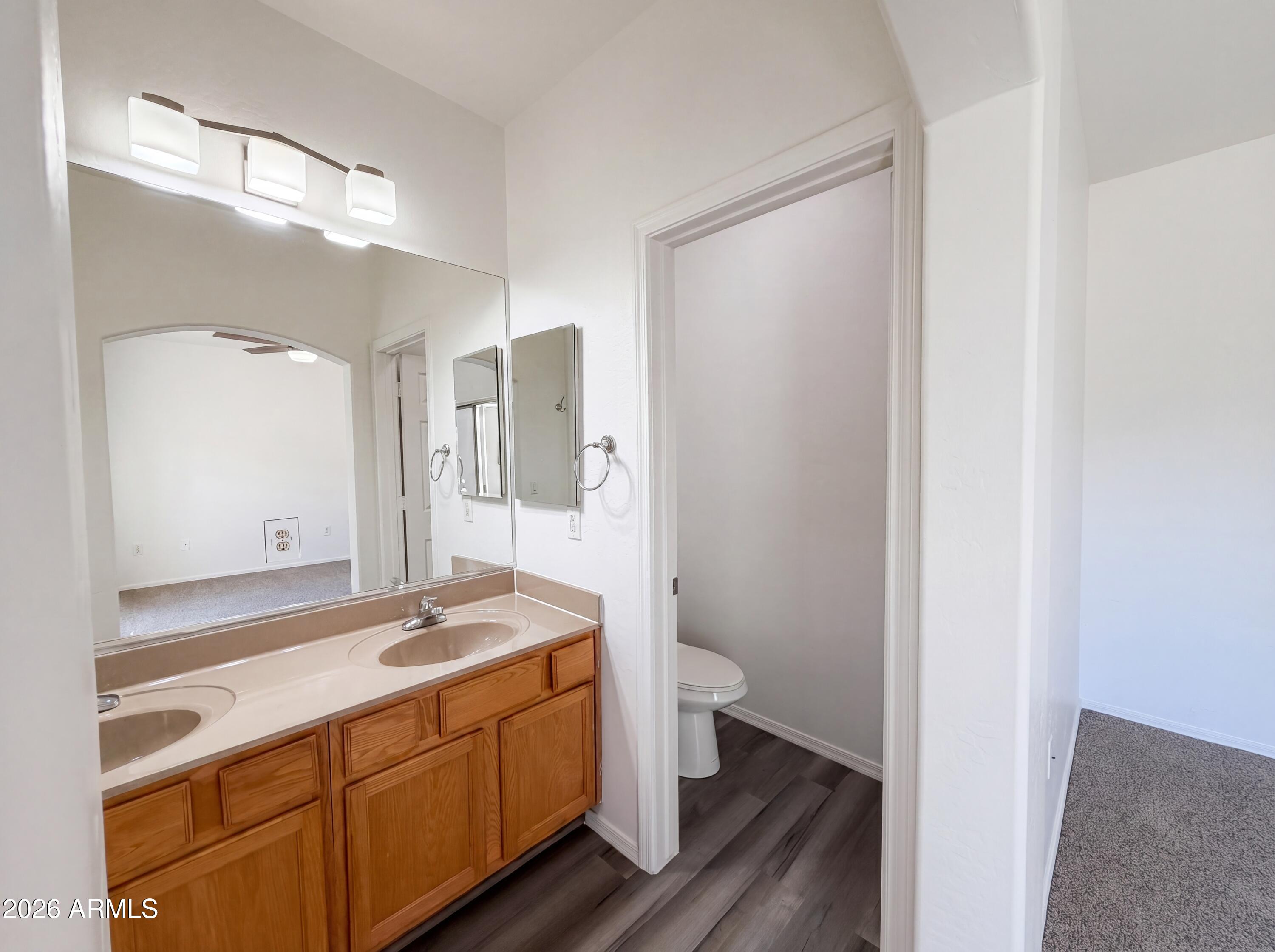 1718 West Colter Street, Unit 174 Phoenix, AZ 85015 - Photo 13 of 21 a bathroom with a double vanity sink a toilet and a mirror