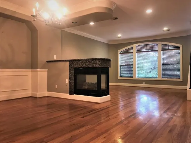 an empty room with wooden floor fireplace and windows