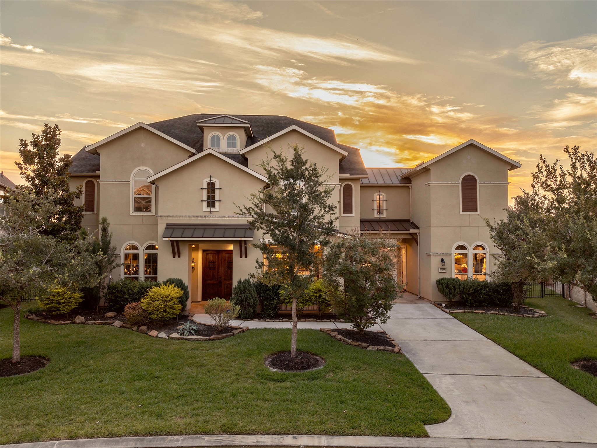 9842 Kirkstone Terrace Drive Spring, TX 77379 - Photo 3 of 34 This beautiful two-story home features a classic design with a light exterior, large windows, and a well-maintained front yard. The driveway leads to an inviting entrance, surrounded by lush landscaping, and is set against a stunning sunset backdrop.
