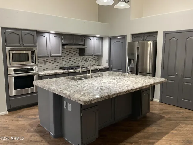 a kitchen with granite countertop kitchen island stainless steel appliances a sink stove and refrigerator