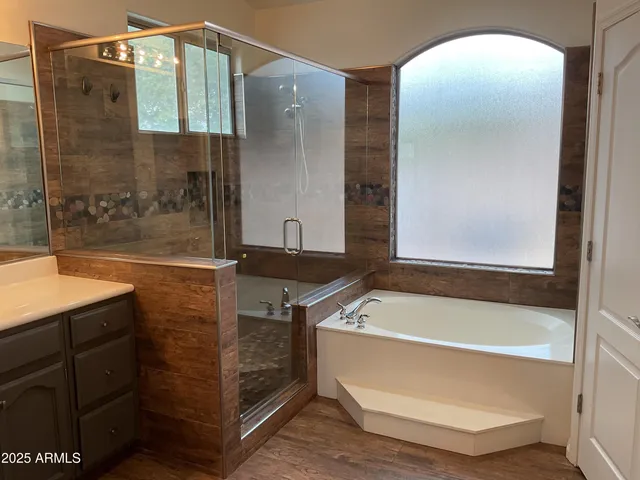 a bathroom with a tub a mirror and a shower