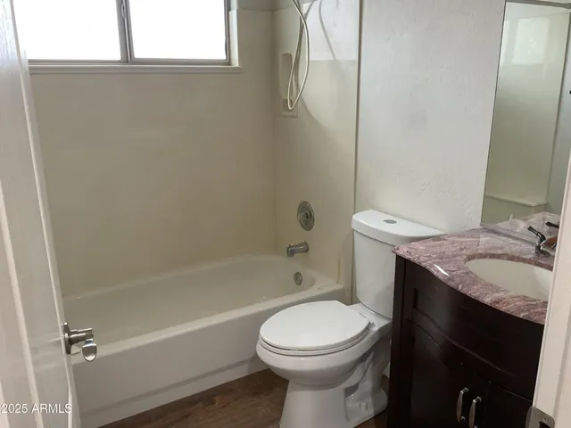 a bathroom with a granite countertop bathtub shower sink vanity and toilet