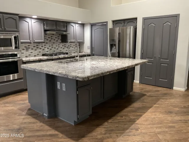 a kitchen with stainless steel appliances granite countertop a refrigerator and a stove