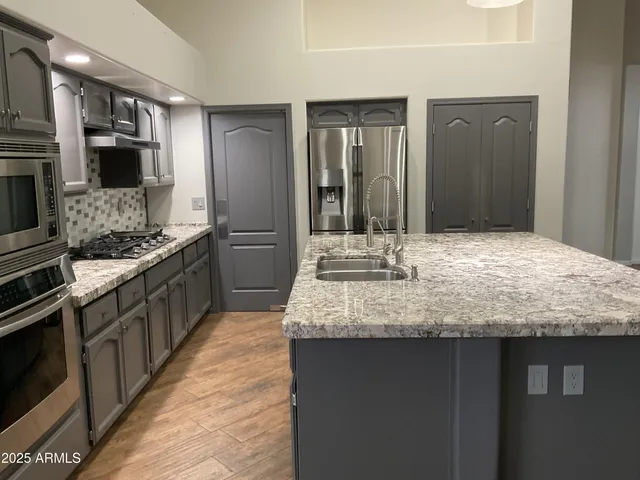 a kitchen with kitchen island granite countertop a sink and stainless steel appliances