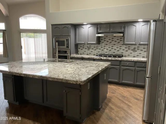 a kitchen with stainless steel appliances granite countertop wooden cabinets and a sink