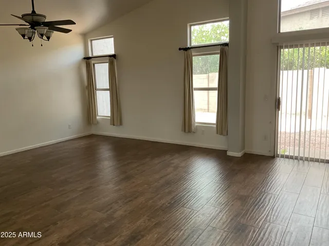 an empty room with wooden floor chandelier and windows