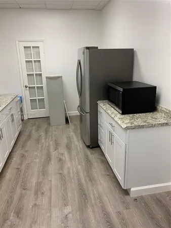 a kitchen with a refrigerator stove and wooden floor