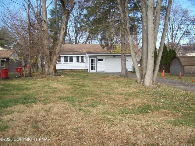a view of a yard in front of a house with large trees