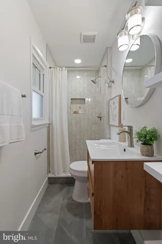 a bathroom with a sink a toilet and shower a mirror