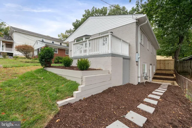 a view of a white house next to a yard with big trees