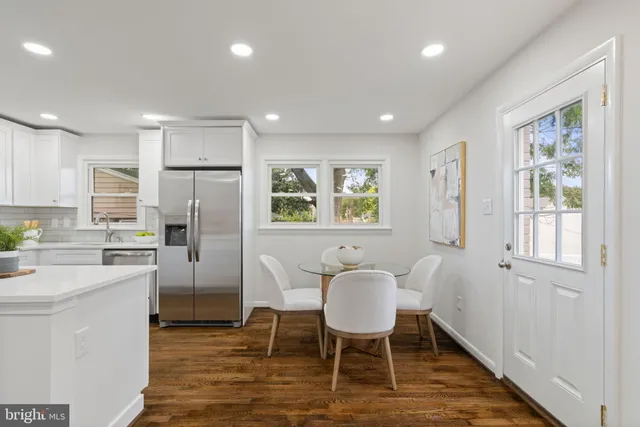 a kitchen with stainless steel appliances a dining table chairs refrigerator and sink