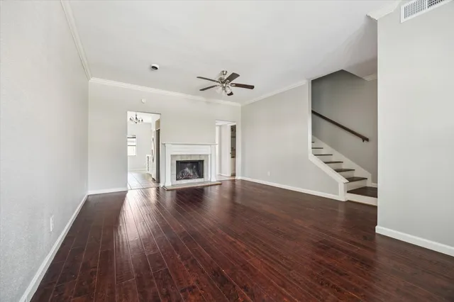 an empty room with wooden floor a chandelier fan a ceiling fan and windows