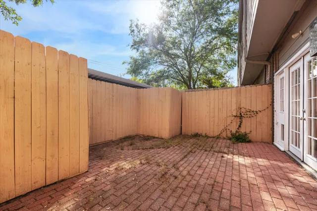 a view of backyard with white wall wooden fence and plants