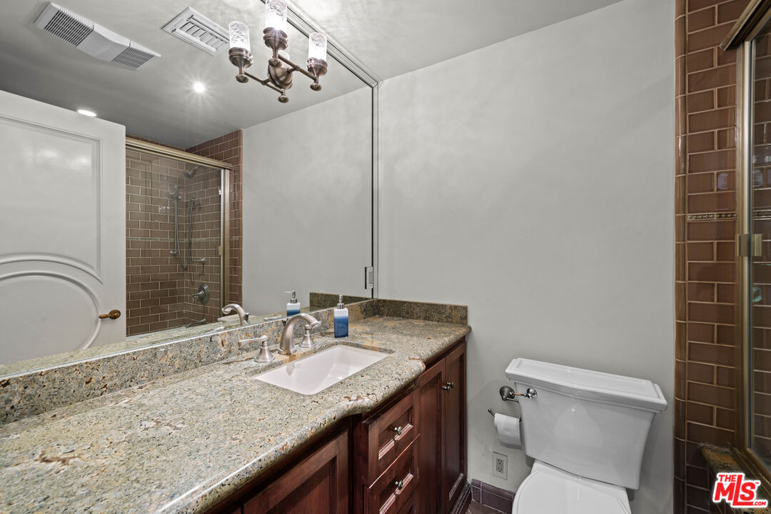 1575 Alexis Place Beverly Hills, CA 90210 - Photo 35 of 75 a bathroom with a granite countertop sink a toilet and a mirror