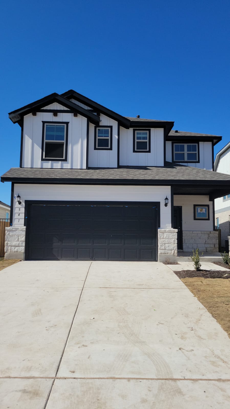 The property features a two-story facade with white siding and dark trim, accented by stone detailing on the lower level