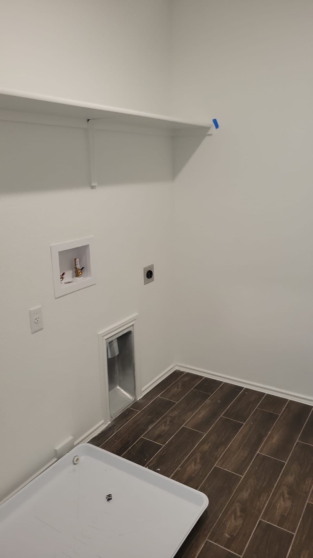 541 Pickrell Loop Georgetown, TX 78628 - Photo 16 of 32 The utility area features a white wall shelf, dark wood-look tile flooring, and white baseboards