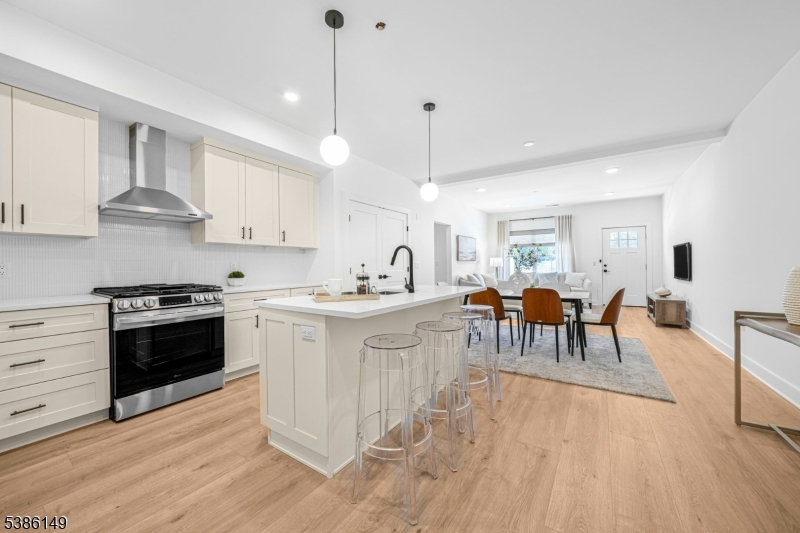 a kitchen with stainless steel appliances kitchen island granite countertop a stove a sink a dining table and chairs with wooden floor