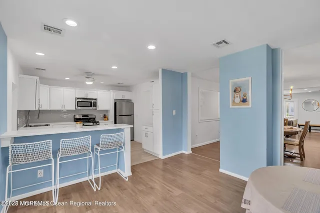 a living room with stainless steel appliances kitchen island granite countertop a sink and a refrigerator