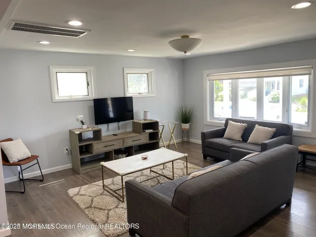 a living room with furniture a flat screen tv and a window